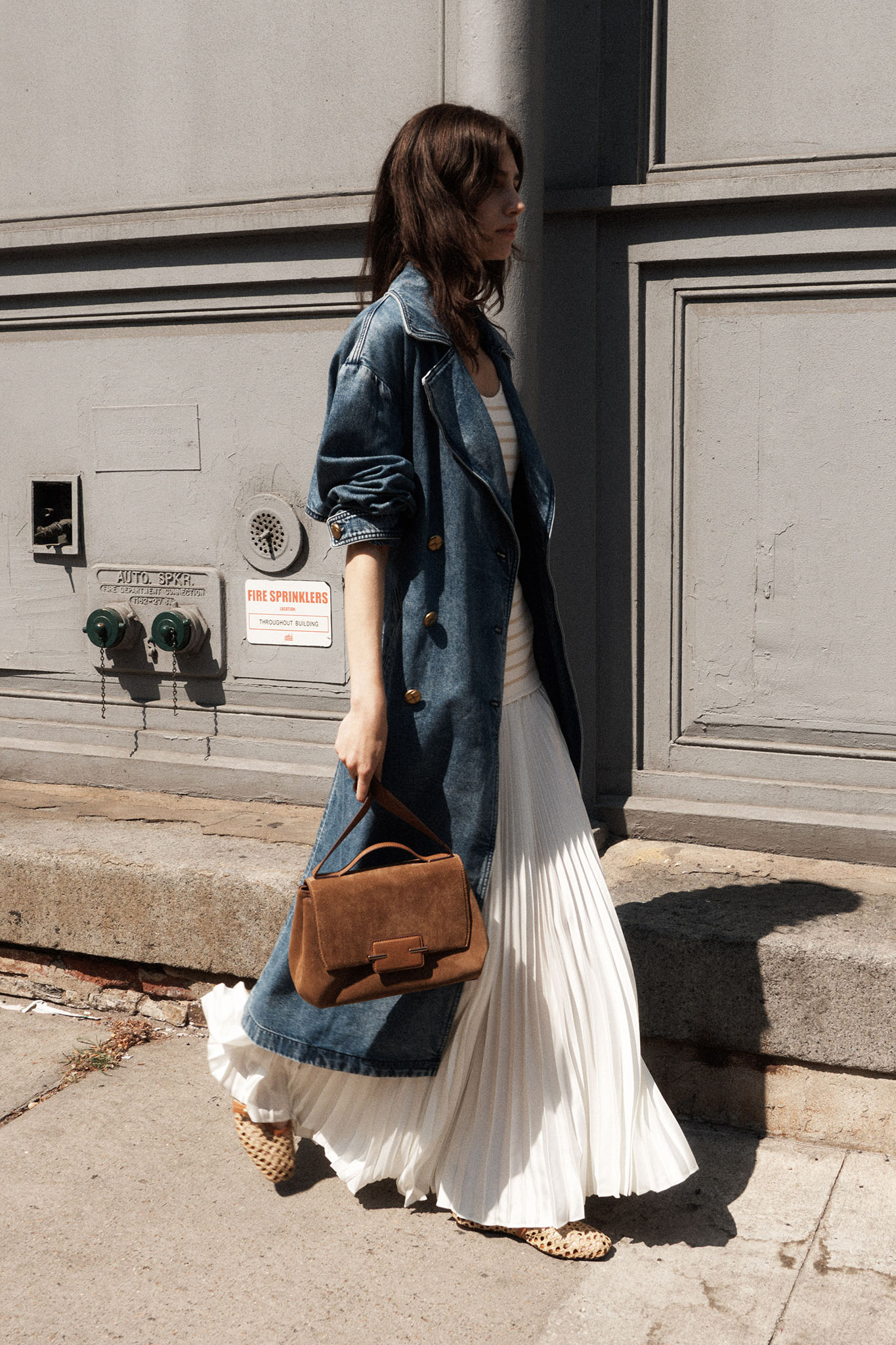 A rag and bones brand model walking on the sidewalk carrying a Signal Brands handbag.