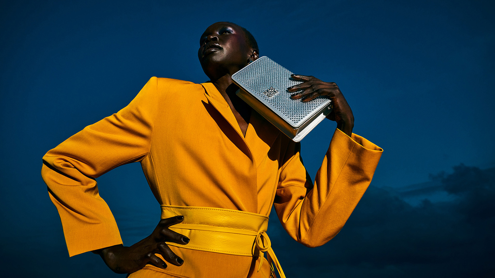 Dramatic photo of a Nine West model wearing a stunning yellow outfit and holding a Signal Brands designed handbag.