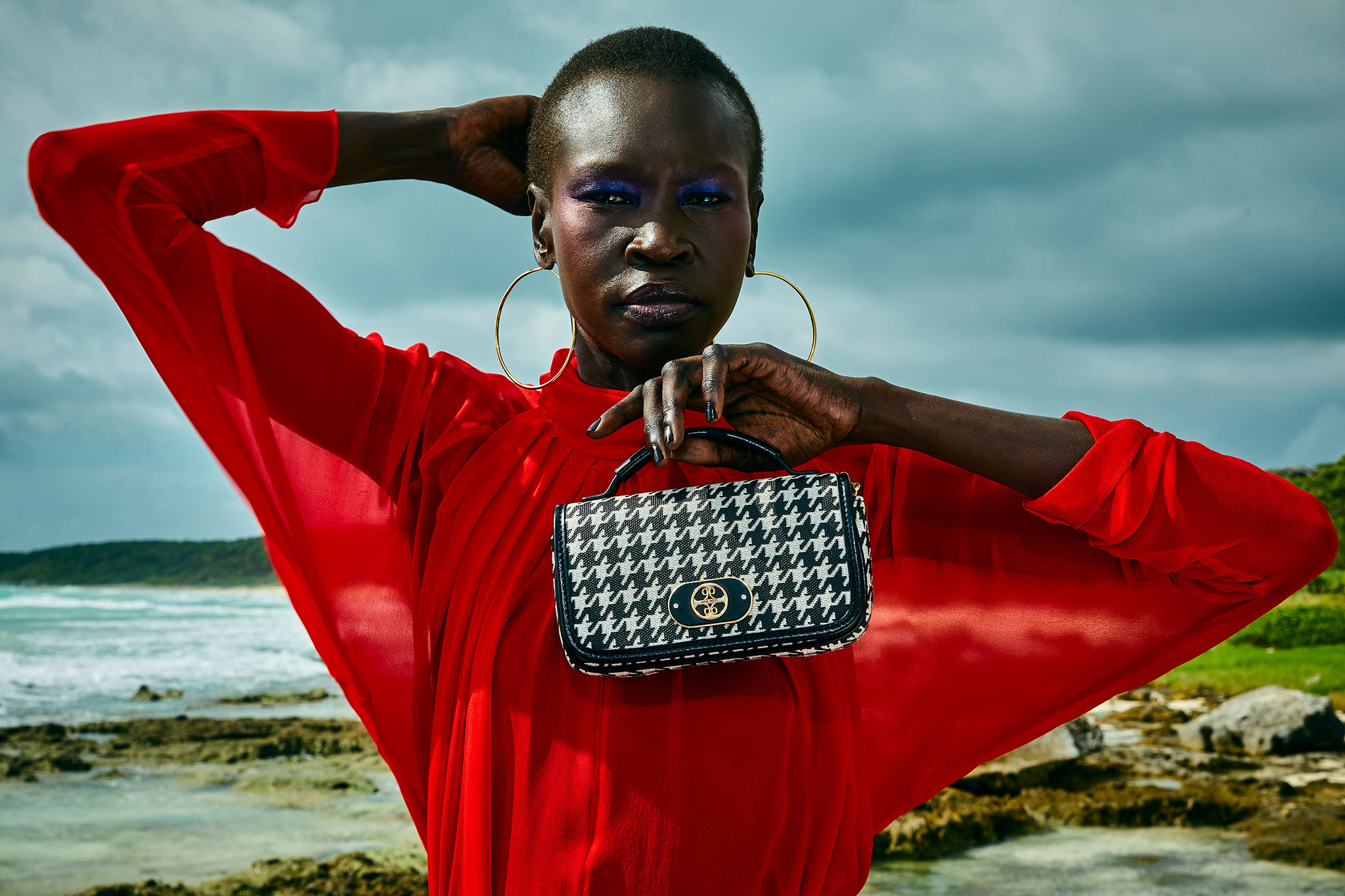 A photo of a Nine West model, wearing a stunning red shirt and holding a Signal Brands handbag